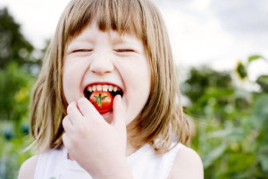 Young Girl(5-6) biting into cherry tomato